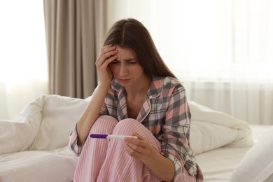 Photo of Woman with negative pregnancy test on bed at home