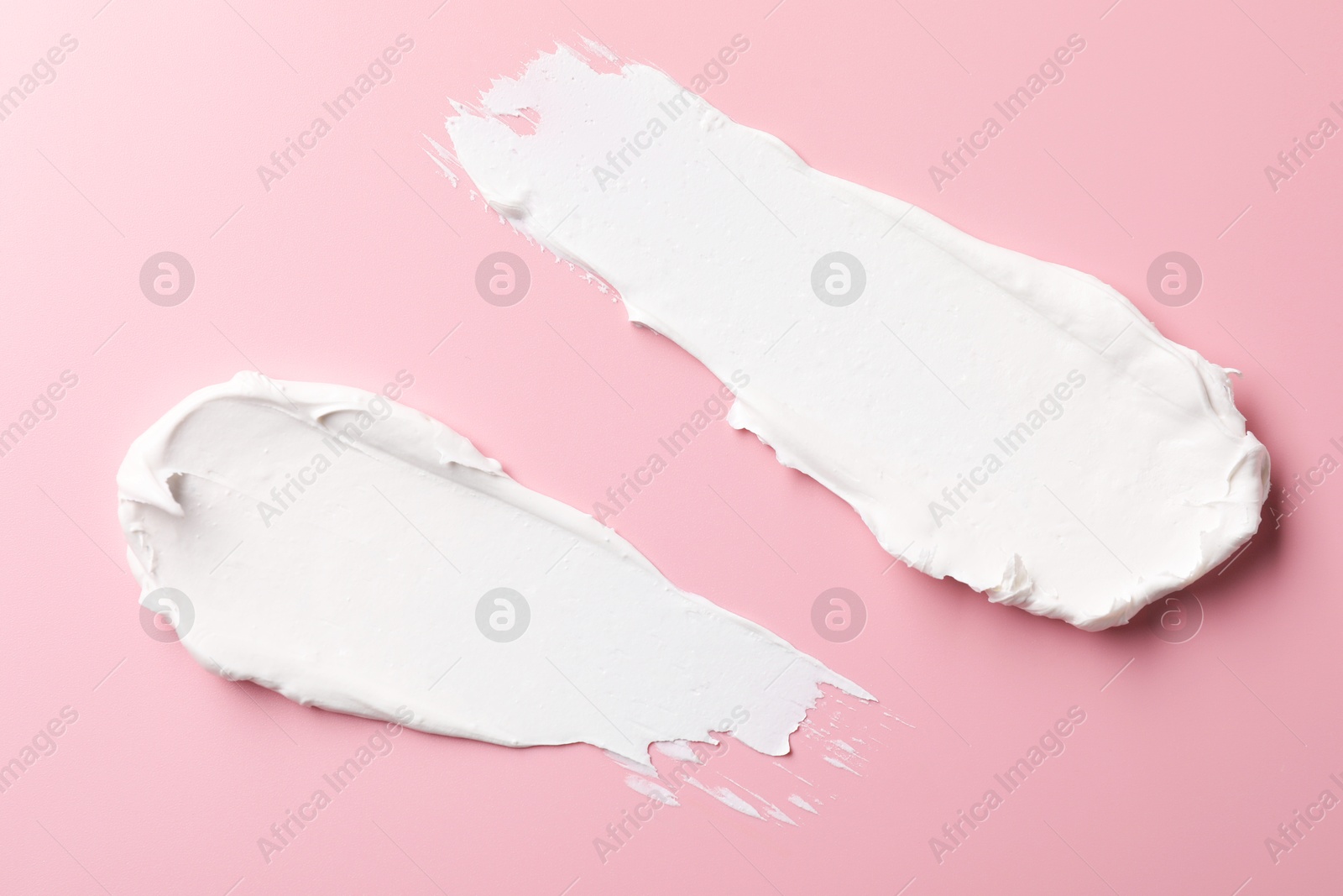 Photo of Cream on pink background, top view. Samples of cosmetic product