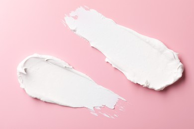 Photo of Cream on pink background, top view. Samples of cosmetic product