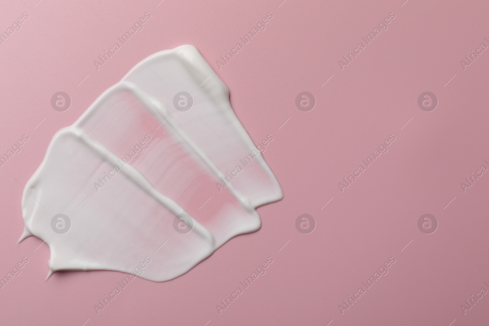 Photo of Cream on pink background, top view and space for text. Sample of cosmetic product