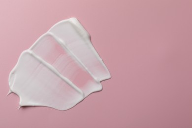 Photo of Cream on pink background, top view and space for text. Sample of cosmetic product