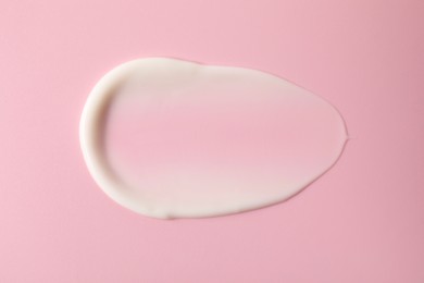 Photo of Cream on pink background, top view. Sample of cosmetic product