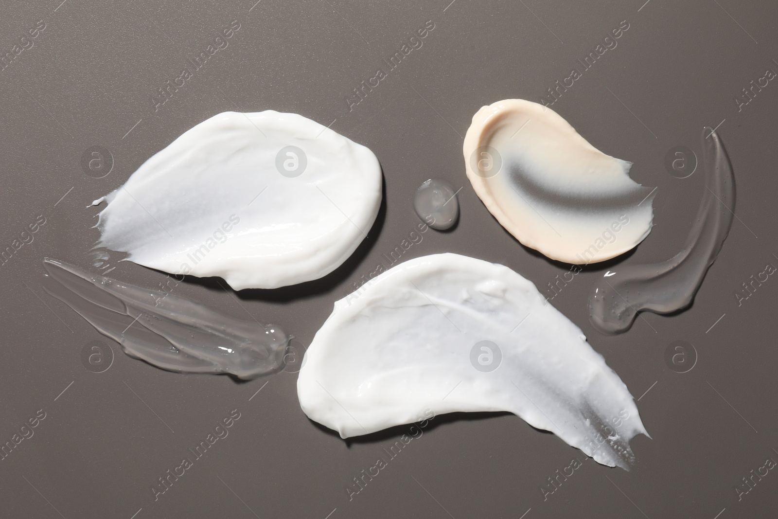 Photo of Samples of different cosmetic products on grey background, flat lay