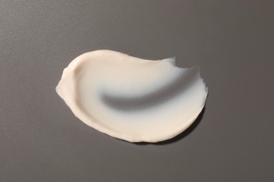 Photo of Cream on grey background, top view. Sample of cosmetic product