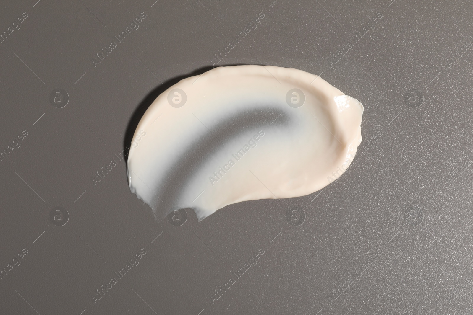 Photo of Cream on grey background, top view. Sample of cosmetic product