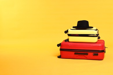 Photo of Packed suitcases and hat on yellow background. Space for text