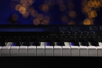 Photo of Piano against blurred lights, closeup. Bokeh effect