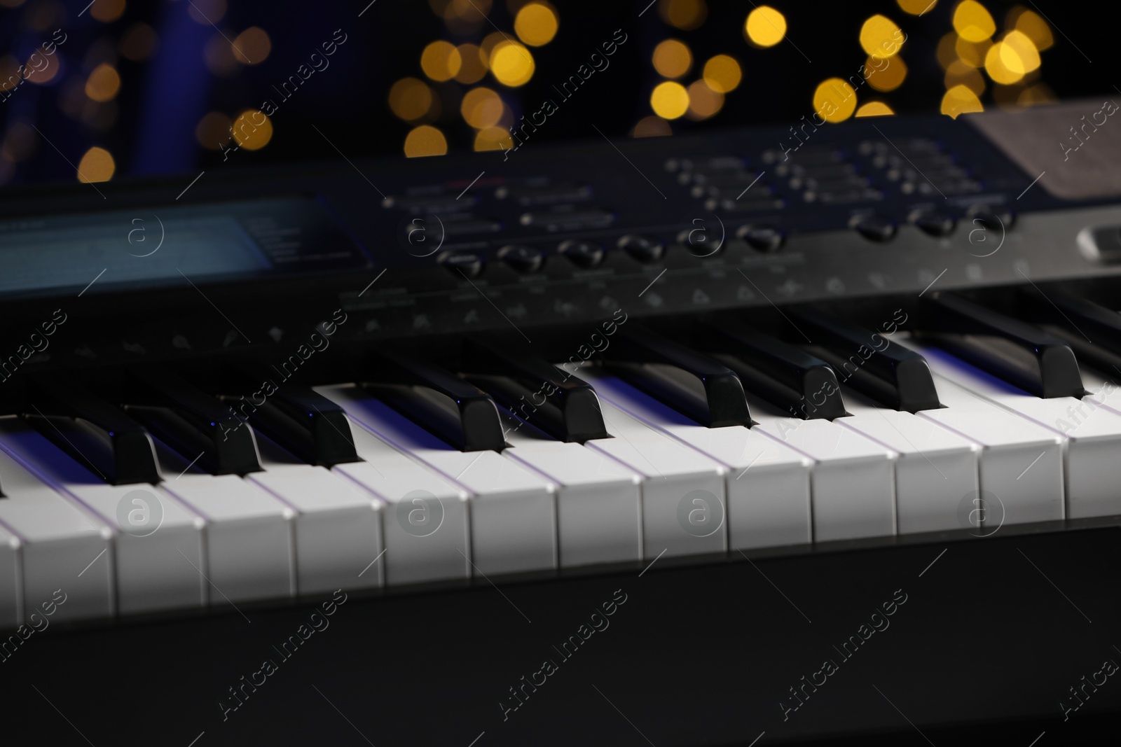 Photo of Piano against blurred lights, closeup. Bokeh effect