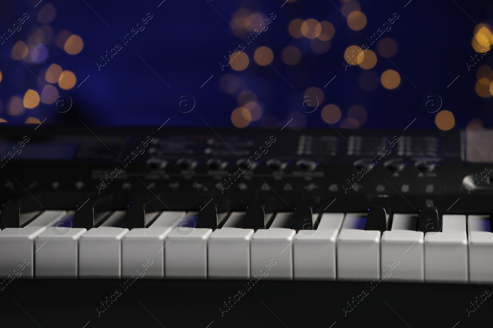 Photo of Piano against blurred lights, closeup. Bokeh effect