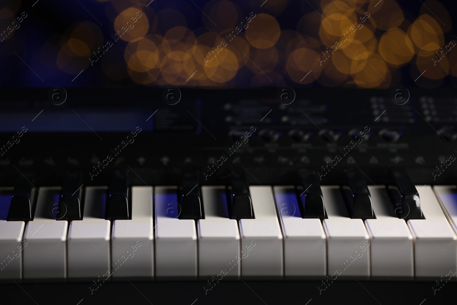 Photo of Piano against blurred lights, closeup. Bokeh effect