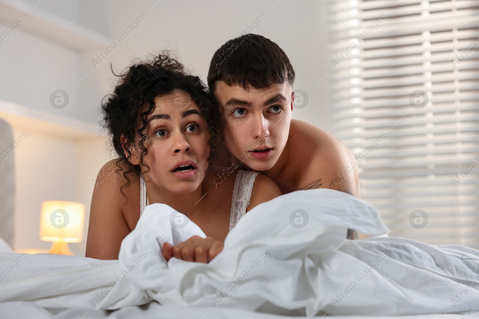 Photo of Betrayal. Shocked lovers on bed at home