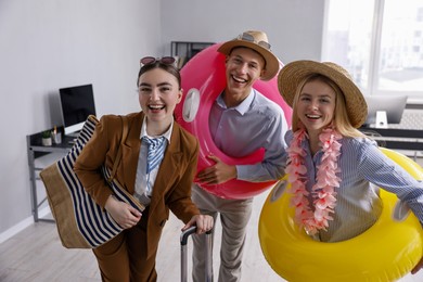 Photo of Colleagues with different beach accessories having fun in office