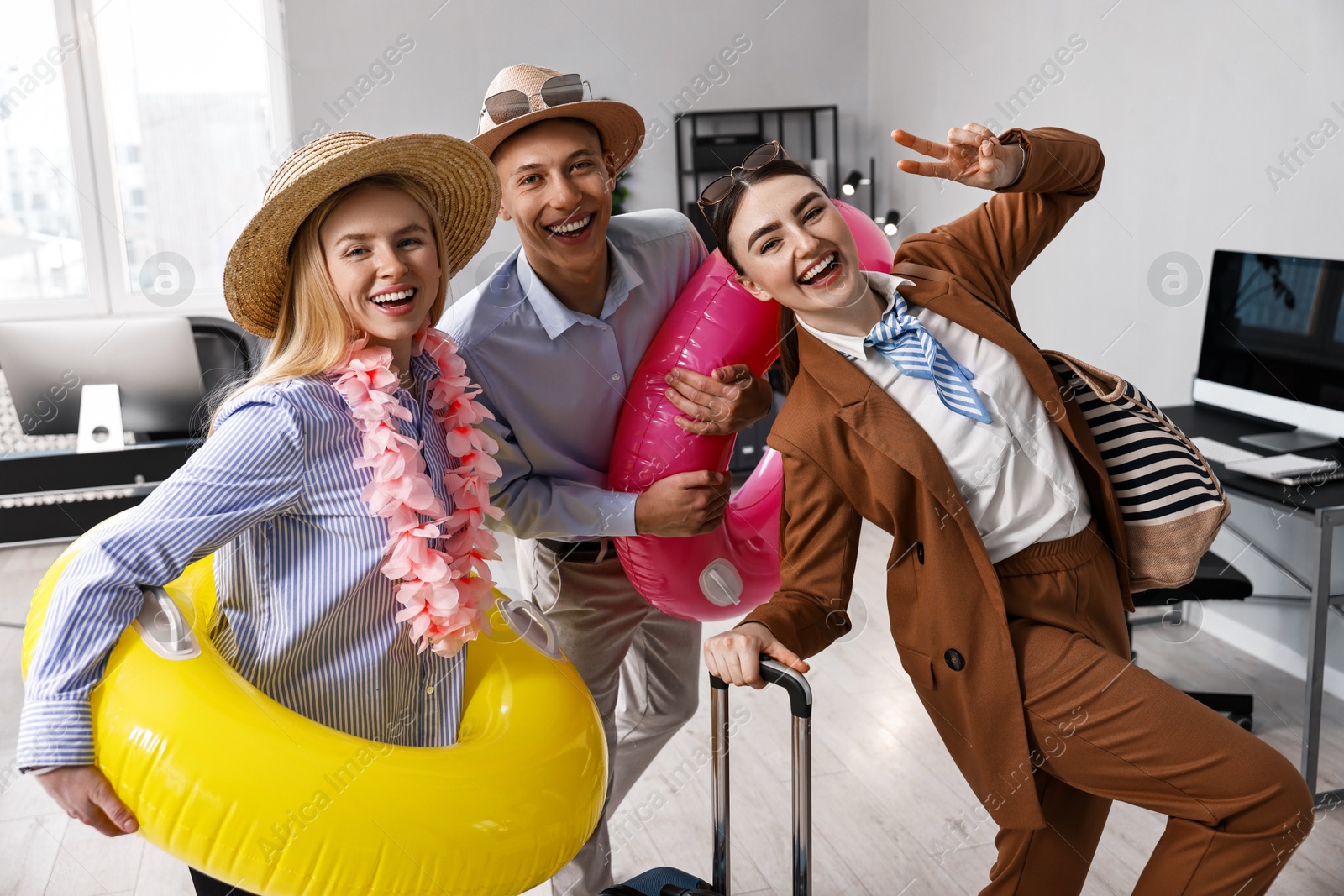 Photo of Colleagues with different beach accessories having fun in office