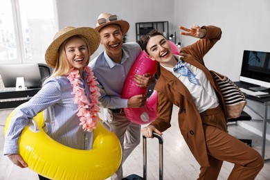 Photo of Colleagues with different beach accessories having fun in office