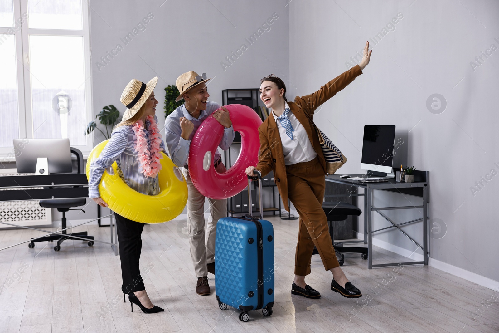 Photo of Colleagues with different beach accessories having fun in office