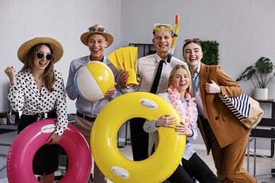 Photo of Colleagues with different beach accessories having fun in office