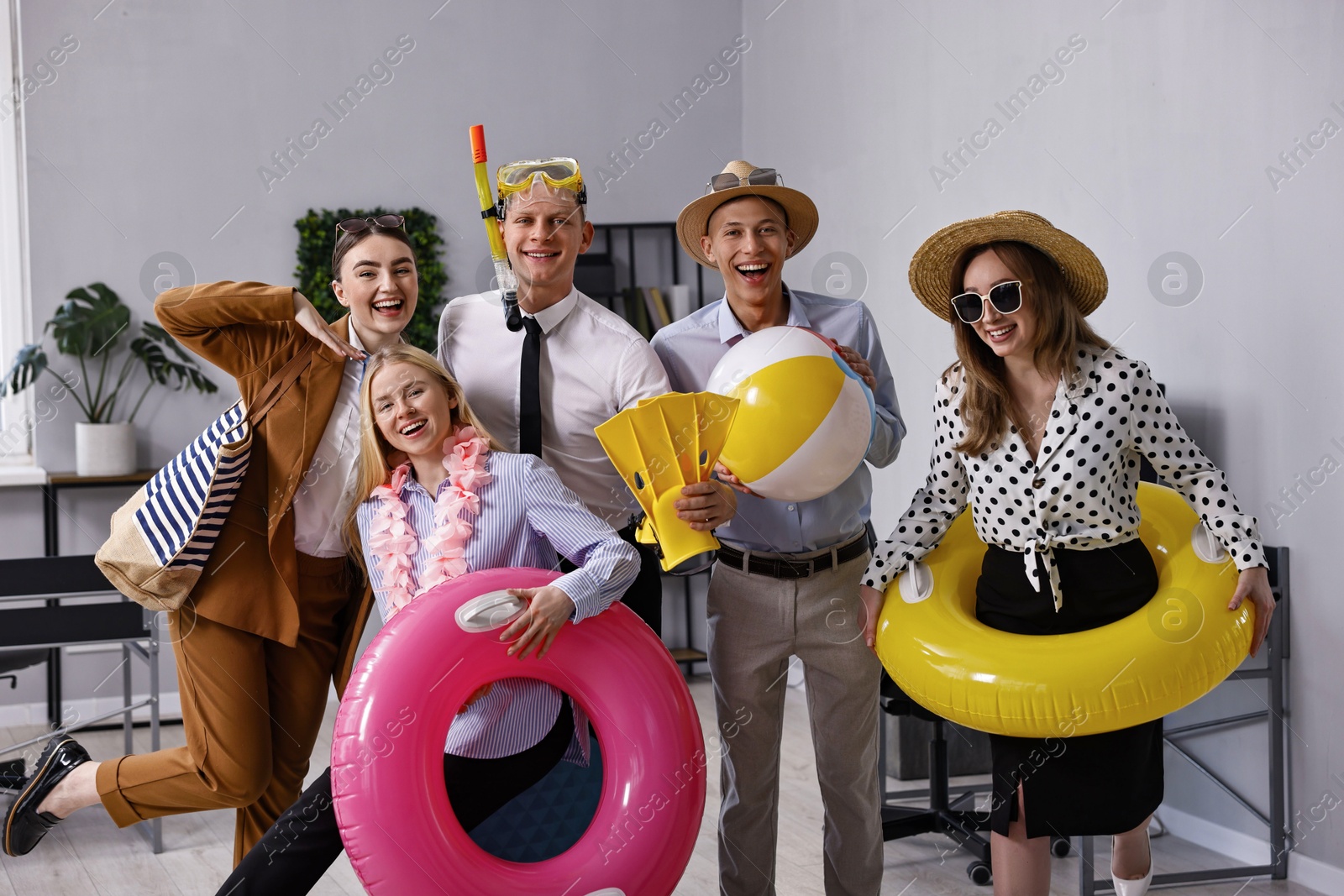 Photo of Colleagues with different beach accessories having fun in office