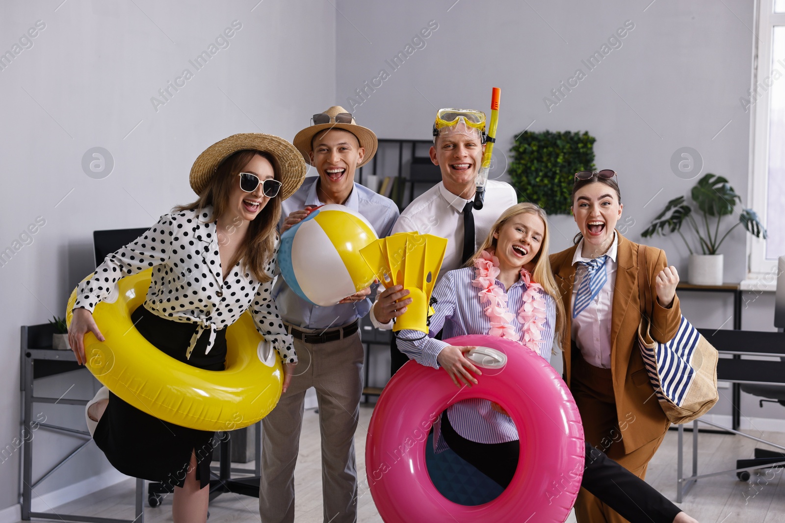 Photo of Colleagues with different beach accessories having fun in office