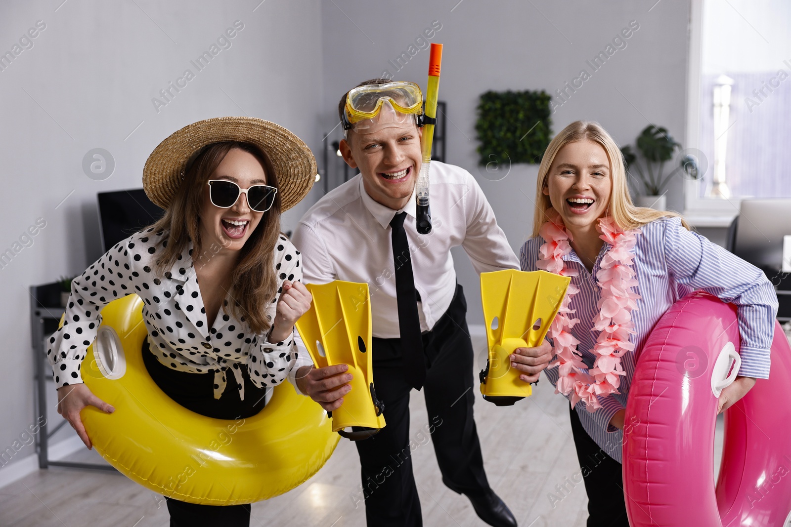 Photo of Colleagues with different beach accessories having fun in office