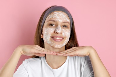 Photo of Teenage girl with cream on her face against pink background. Acne treatment