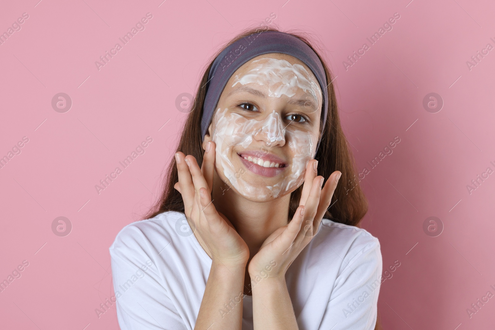 Photo of Teenage girl with cream on her face against pink background. Acne treatment