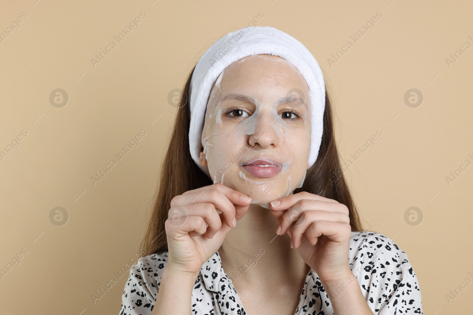 Photo of Teenage girl with sheet facial mask on beige background. Acne treatment