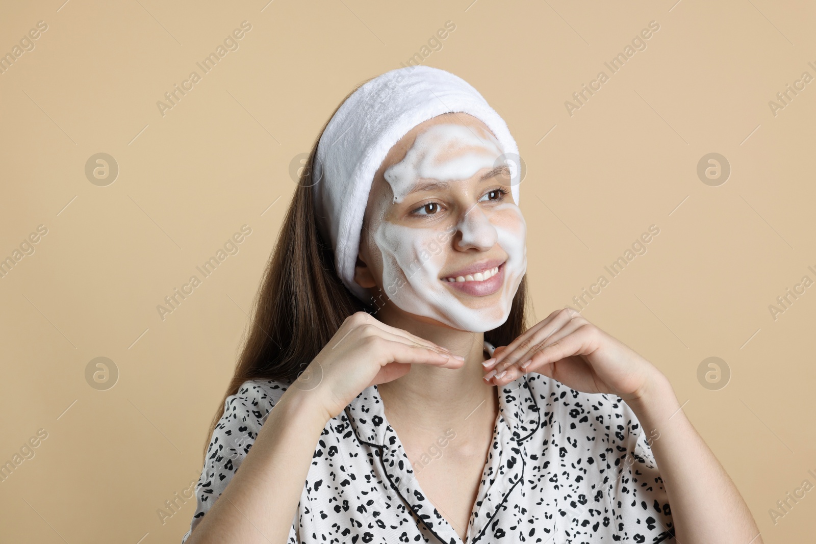 Photo of Teenage girl with cleansing foam on her face against beige background. Acne treatment