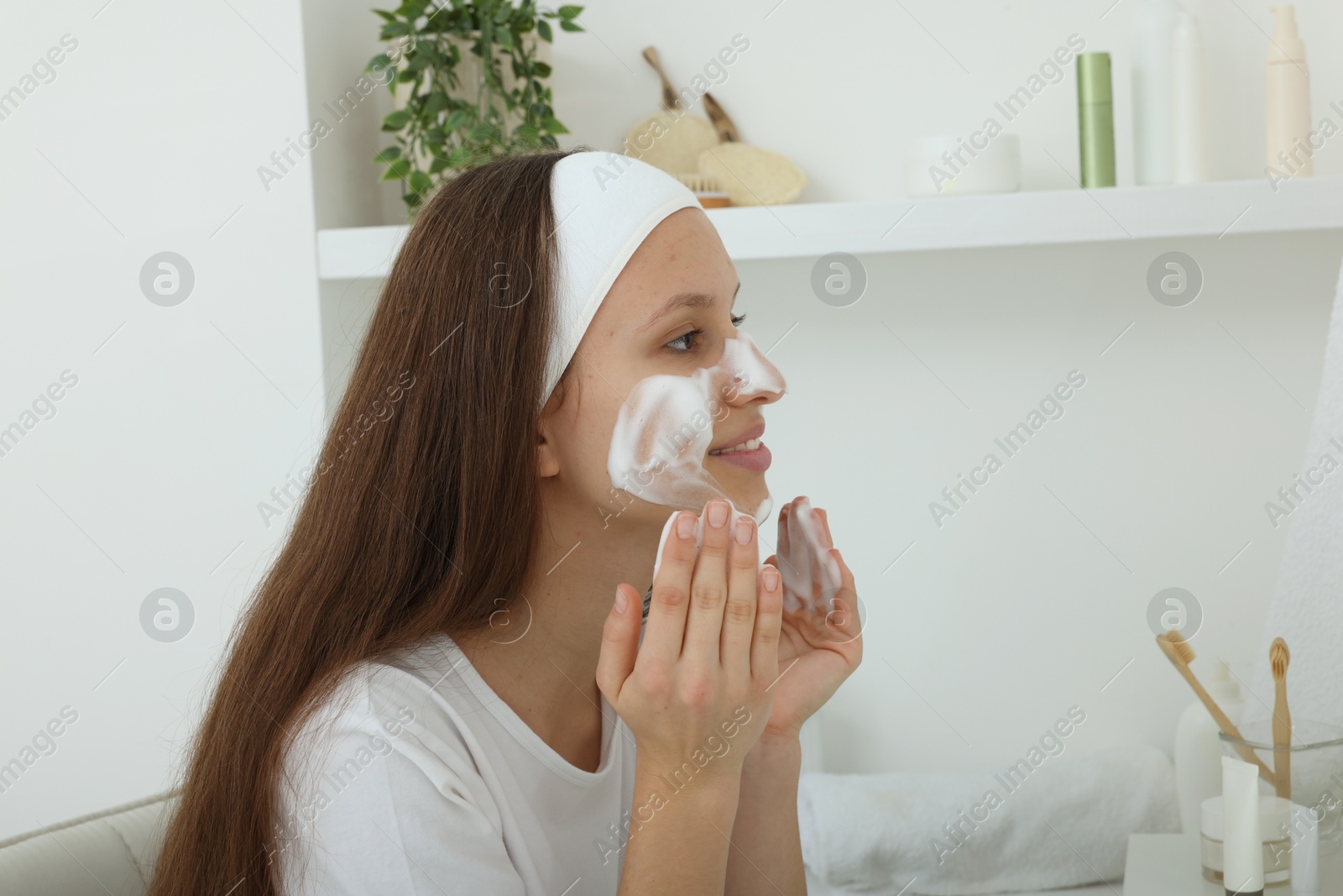 Photo of Teenage girl with cleansing foam on her face at home. Acne treatment