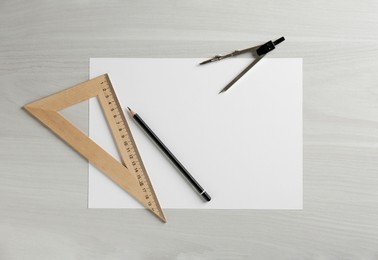 Photo of Paper, ruler, compass and pencil on white wooden table, flat lay. Space for text