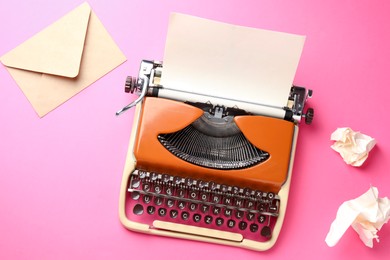 Photo of Vintage typewriter, crumpled paper and envelope on pink background, flat lay