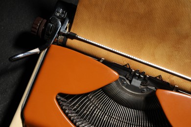 Photo of Vintage typewriter with parchment paper on black background, top view