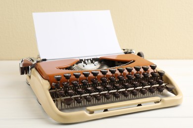 Photo of Vintage typewriter with sheet of paper on white wooden table