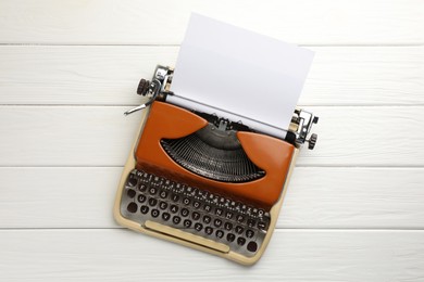 Photo of Vintage typewriter with sheet of paper on white wooden table