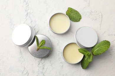 Photo of Mint lip balms and green leaves on beige textured background, flat lay. Cosmetic product