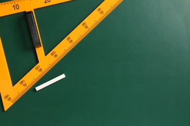 Photo of Triangle ruler and chalk on green chalkboard, top view. Space for text