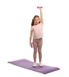 Photo of Cute little girl exercising with dumbbells on mat against white background