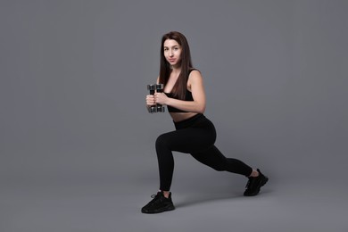 Photo of Woman in sportswear exercising with dumbbells on grey background, space for text