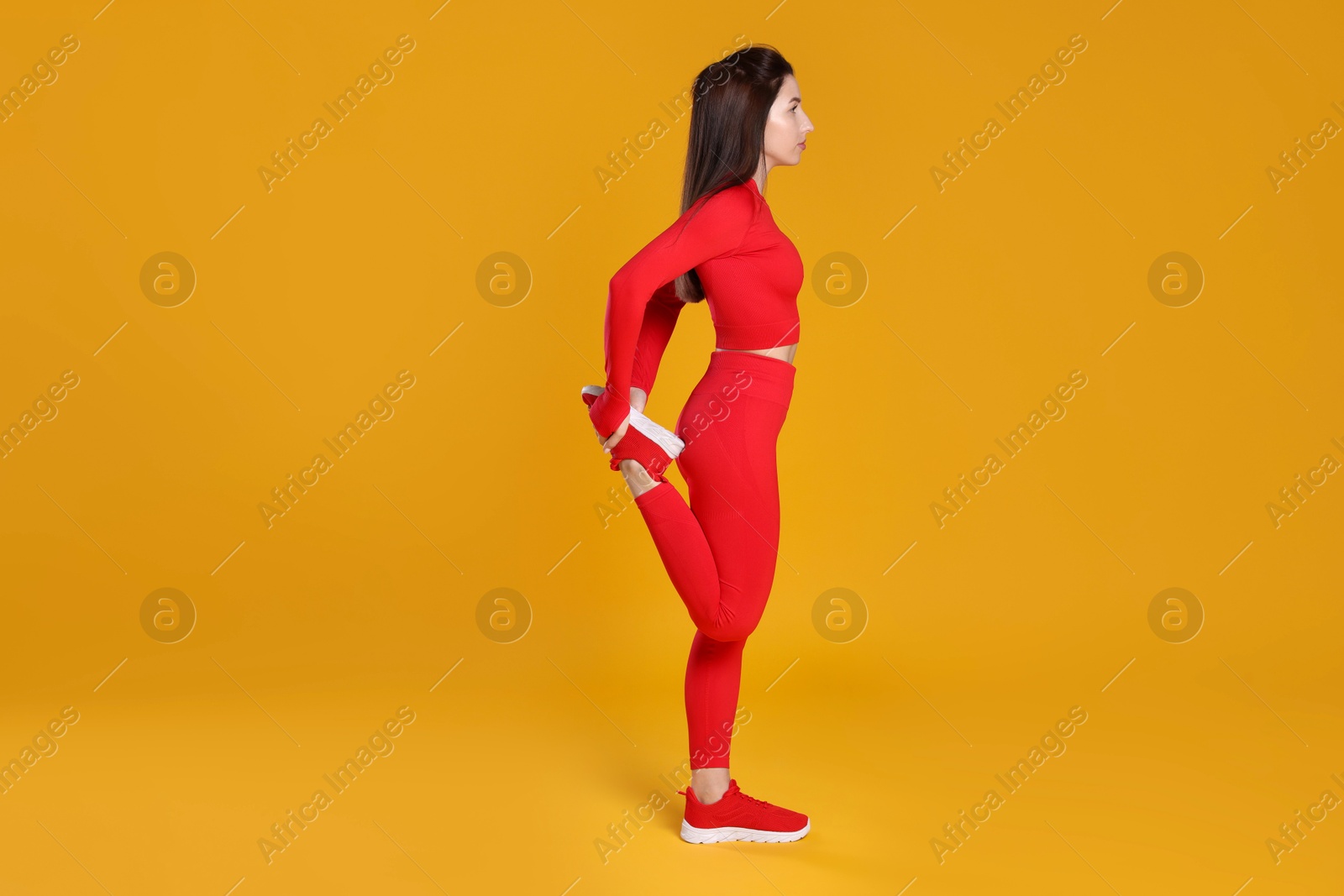 Photo of Woman in sportswear exercising on orange background