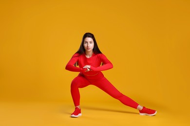 Photo of Woman in sportswear exercising on orange background