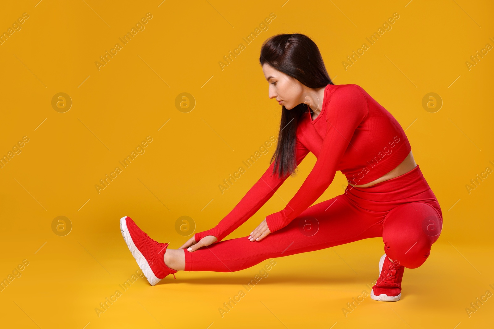 Photo of Woman in sportswear exercising on orange background