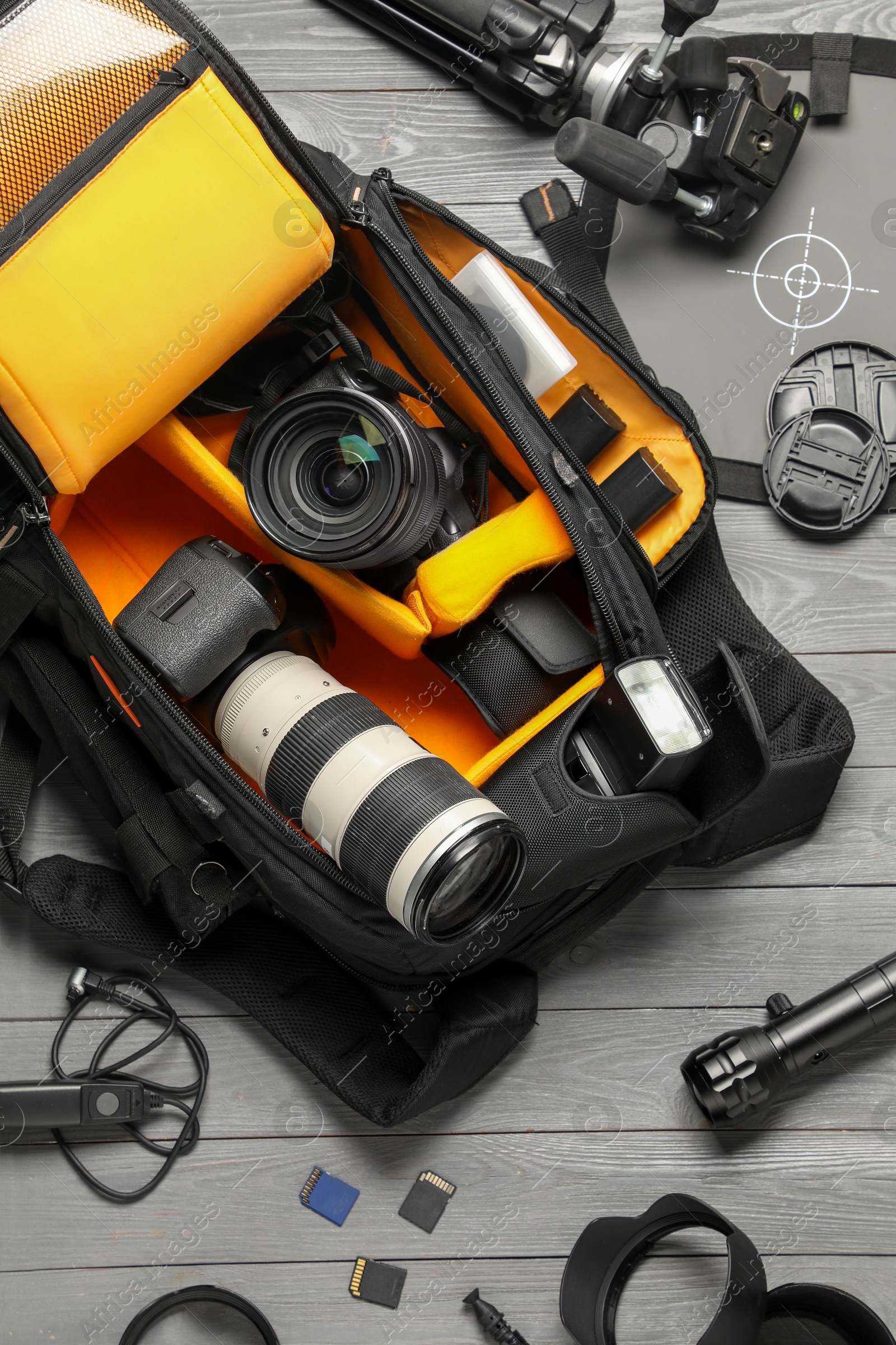 Photo of Professional photographer's equipment and backpack on grey wooden background, flat lay