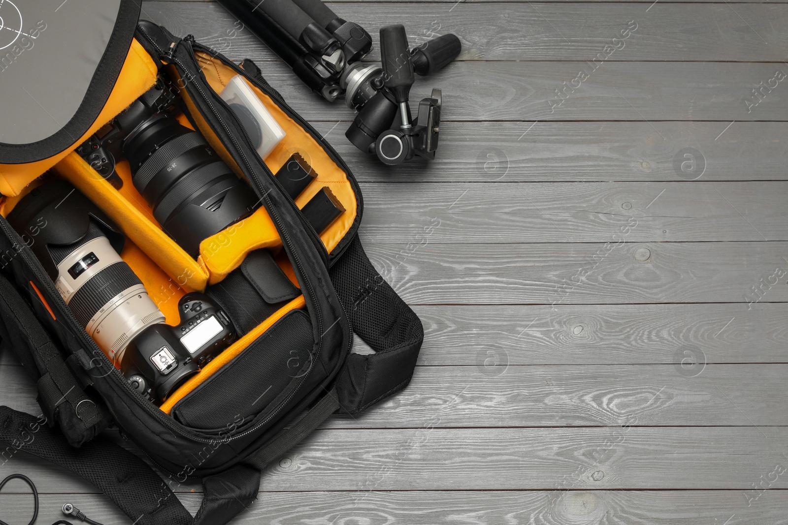 Photo of Professional photographer's equipment and backpack on grey wooden background, flat lay. Space for text