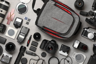 Professional photographer's equipment and backpack on light background, flat lay