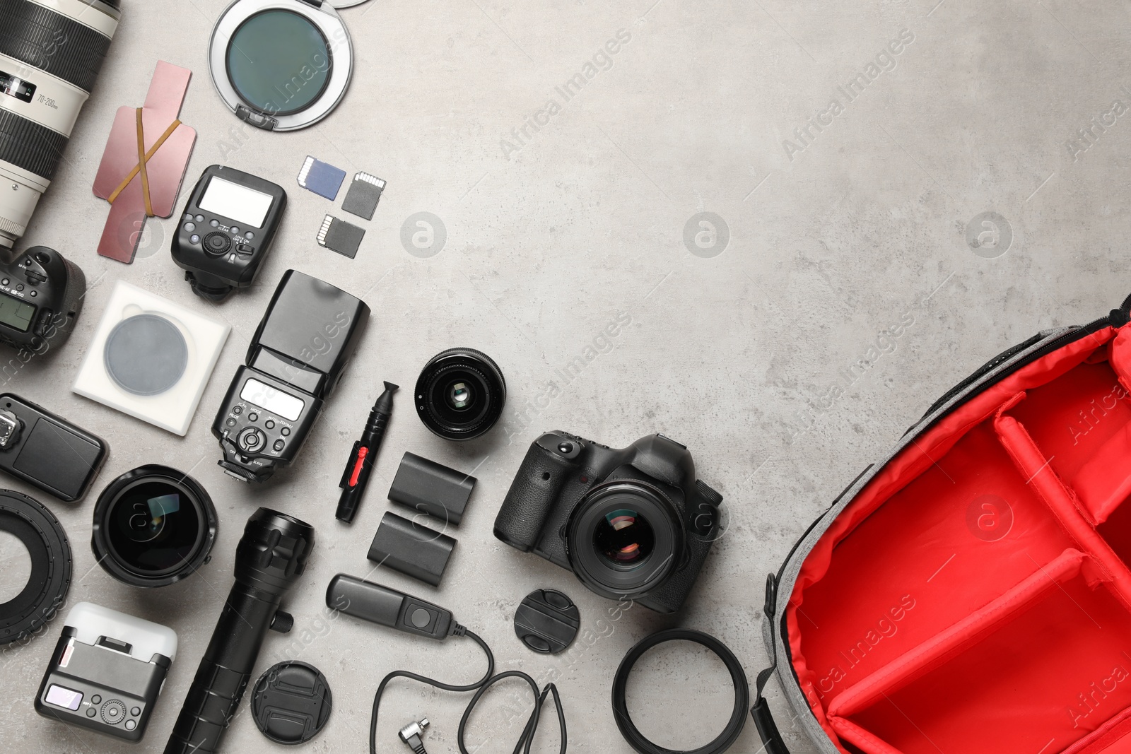 Photo of Professional photographer's equipment and backpack on light background, flat lay. Space for text