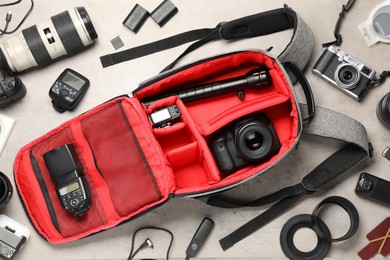 Photo of Professional photographer's equipment and backpack on light background, flat lay