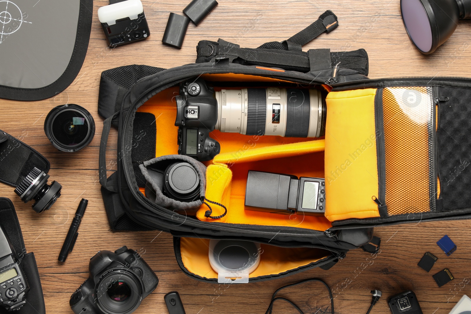 Photo of Professional photographer's equipment and backpack on wooden background, flat lay