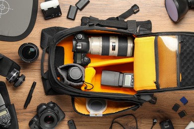 Photo of Professional photographer's equipment and backpack on wooden background, flat lay