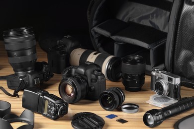 Photo of Professional photographer's equipment and backpack on wooden table