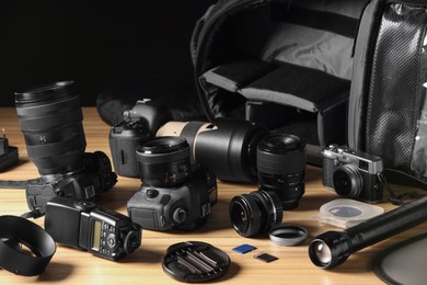 Photo of Professional photographer's equipment and backpack on wooden table