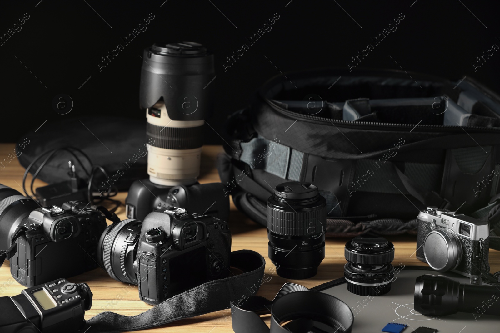 Photo of Professional photographer's equipment and backpack on wooden table